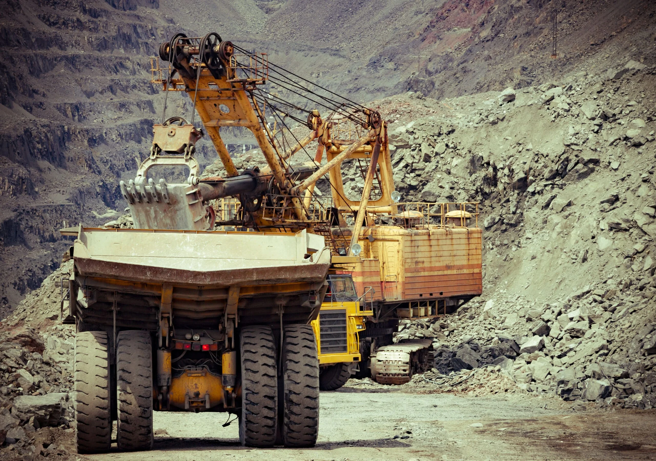 Heavy mining trucks and excavator working on the iron ore opencast mining facility